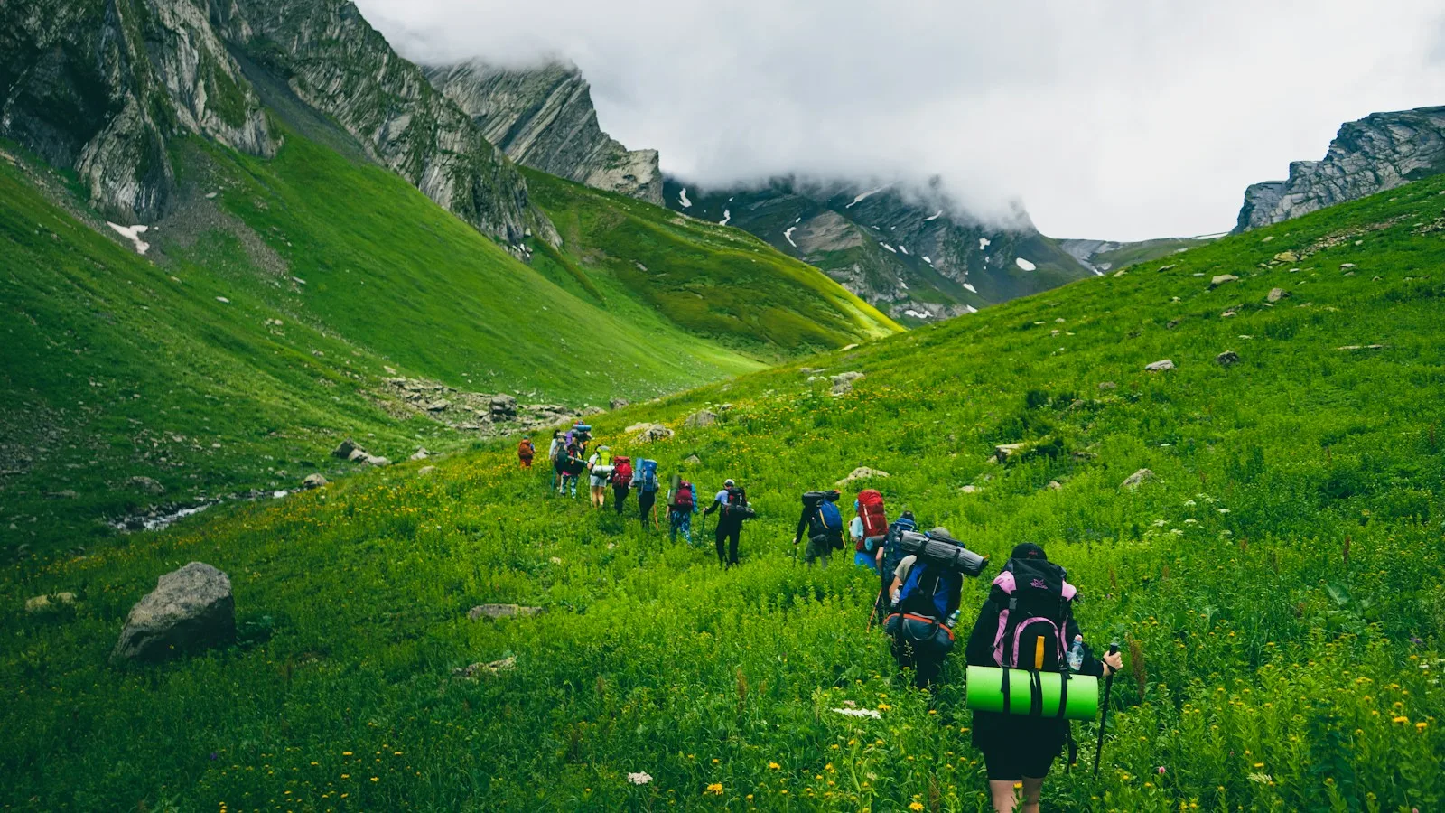Randonneurs sur un chemin de montagne en Svanétie avec vue sur les sommets du Caucase